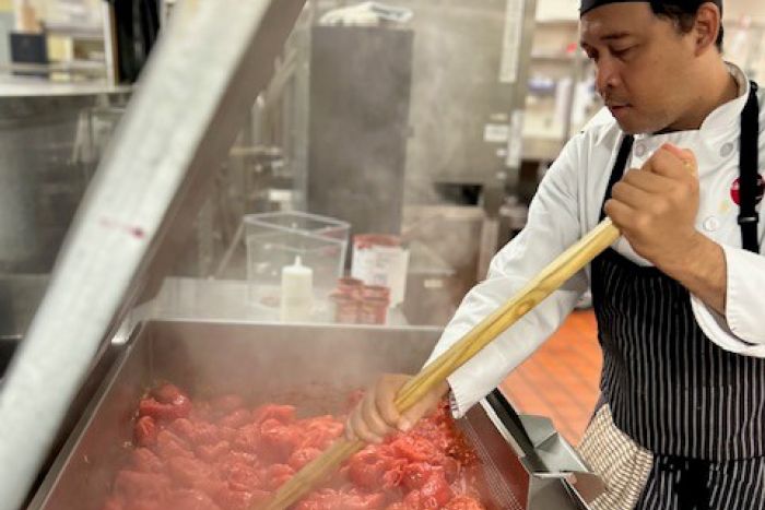 A student chef cooks with tomatoes.