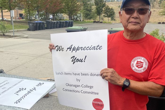 A person holding up a sign thanking wildfire workers.