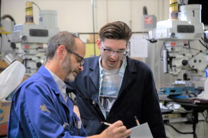 Instructor and student in lab staring at a clipboard, surrounded by sophisticated equipment instructor
