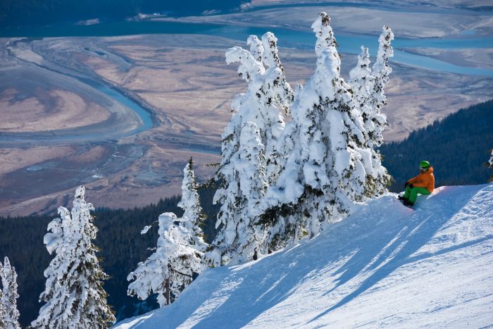 snowboarder sitting at the top of the hill looking down at the vallye
