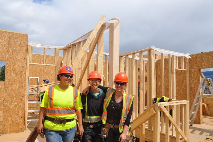 Three female construction workers stand on a construction site