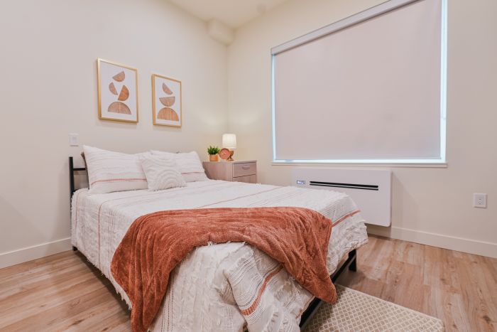 A queen bed positioned beside a window in a bedroom.