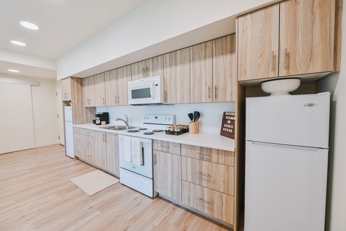 Fully equipped shared kitchen featuring two refrigerators, a countertop with a sink, and ample cabinet storage above and below, providing plenty of space for food preparation and everyday essentials.