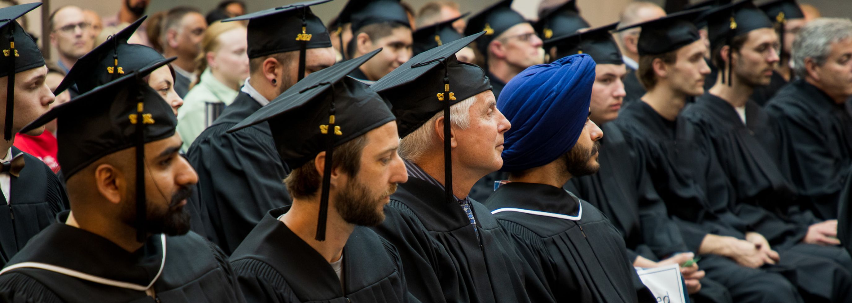 trades students sitting with regalia cap and gown dressed