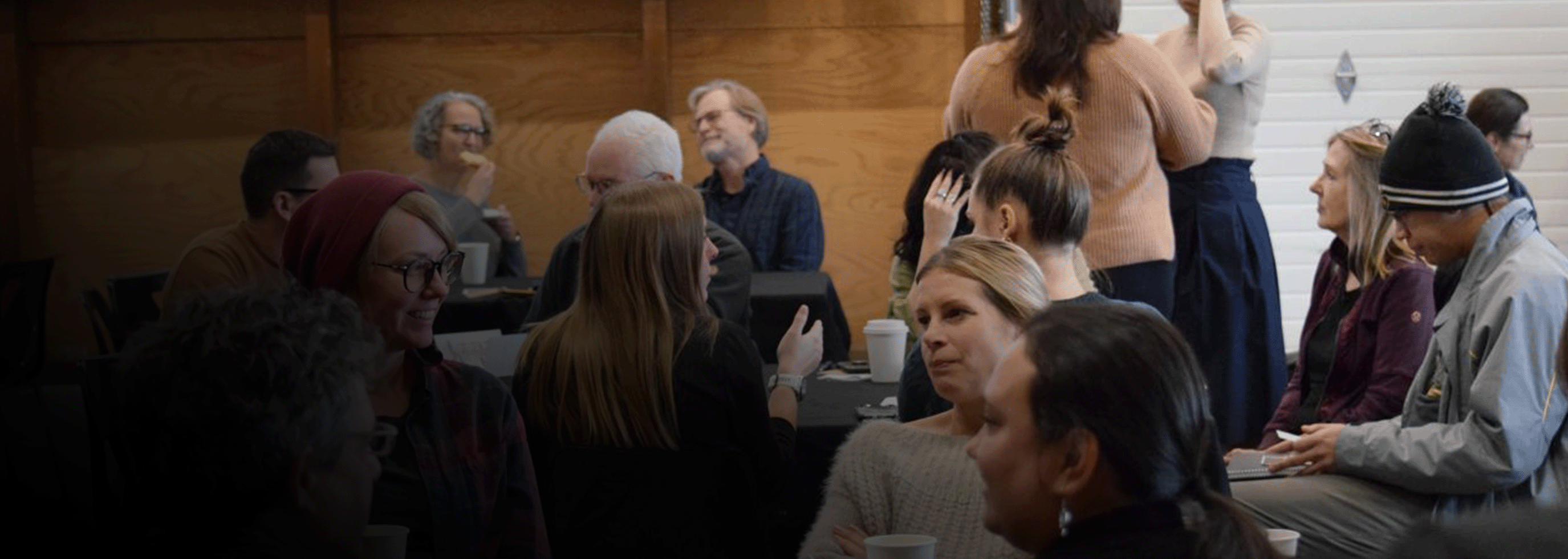 Group of men and women sitting at tables in lively discussion 
