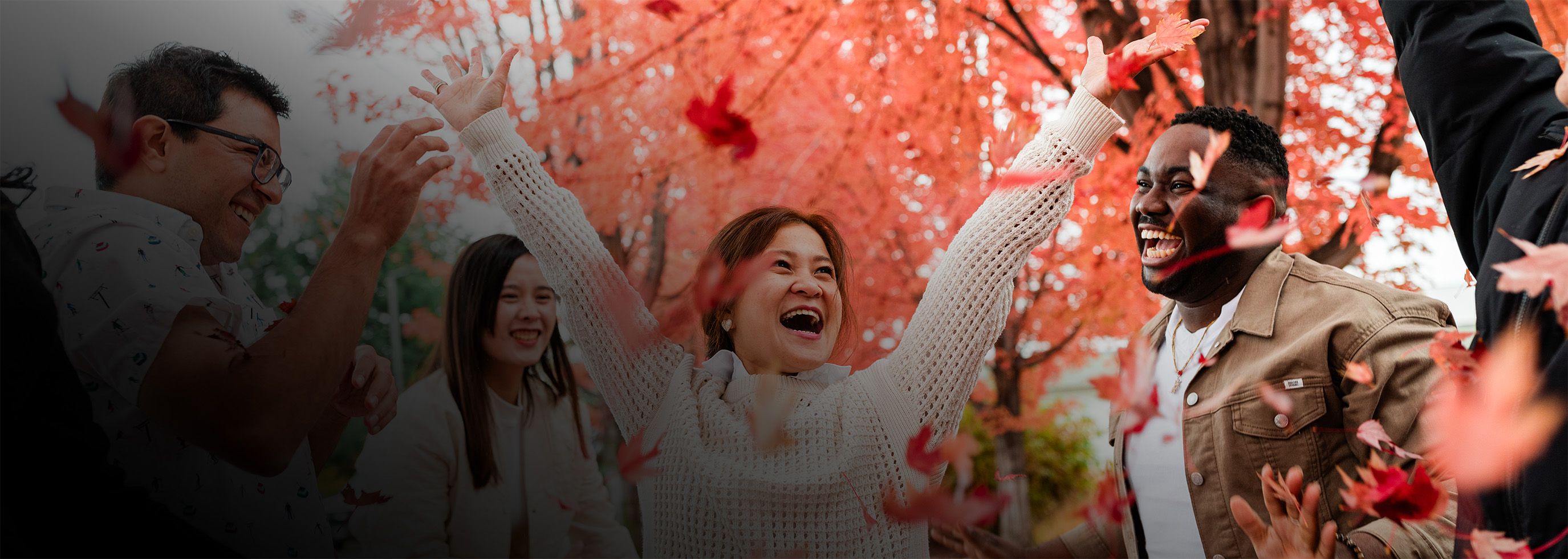 People smile with orange leaves falling around them