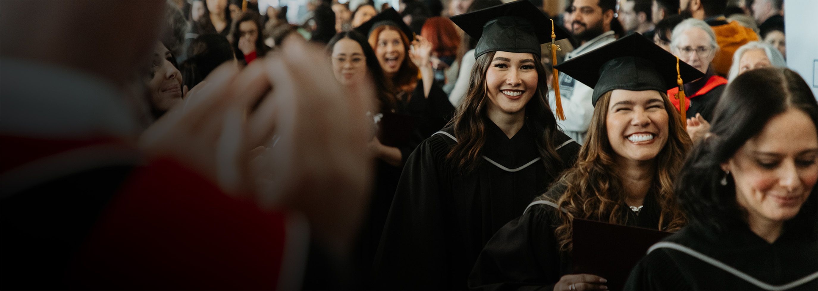 graduates smile while crossing the stage