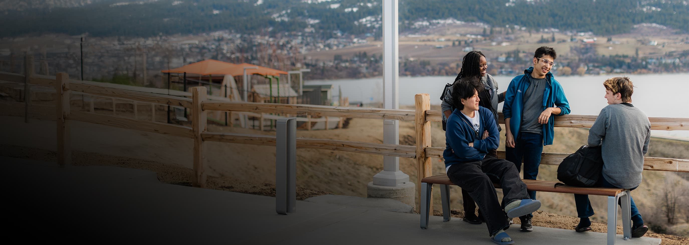 A group of OC students on a bench near a lake, taking in the tranquil scenery and enjoying their time outdoors