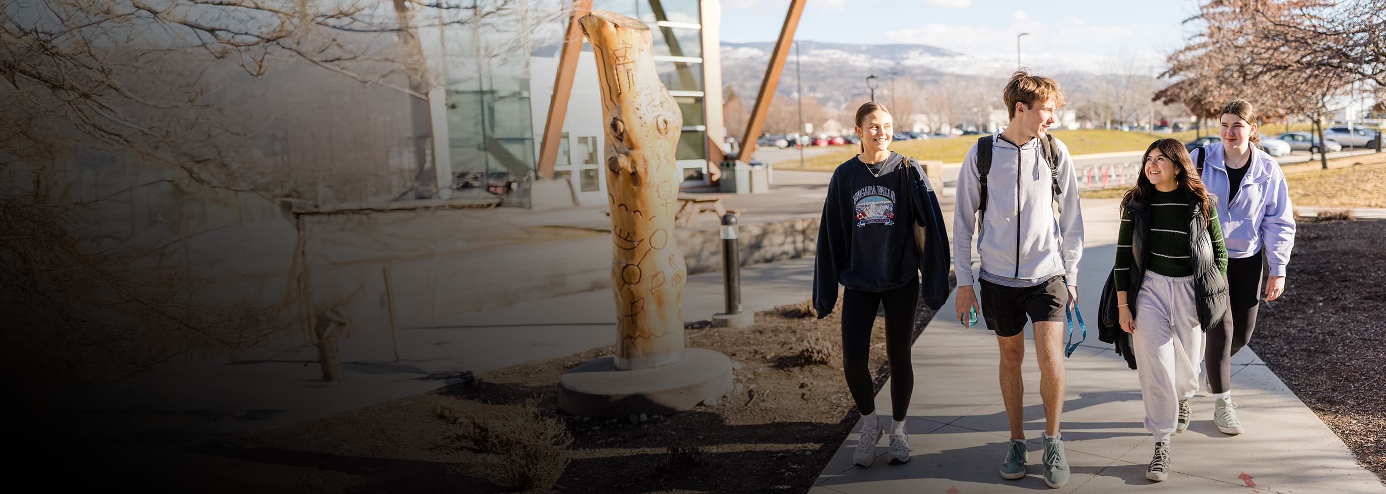 OC students walk together on a sidewalk outside an OC campus building on a sunny day, with mountains visible in the background.
