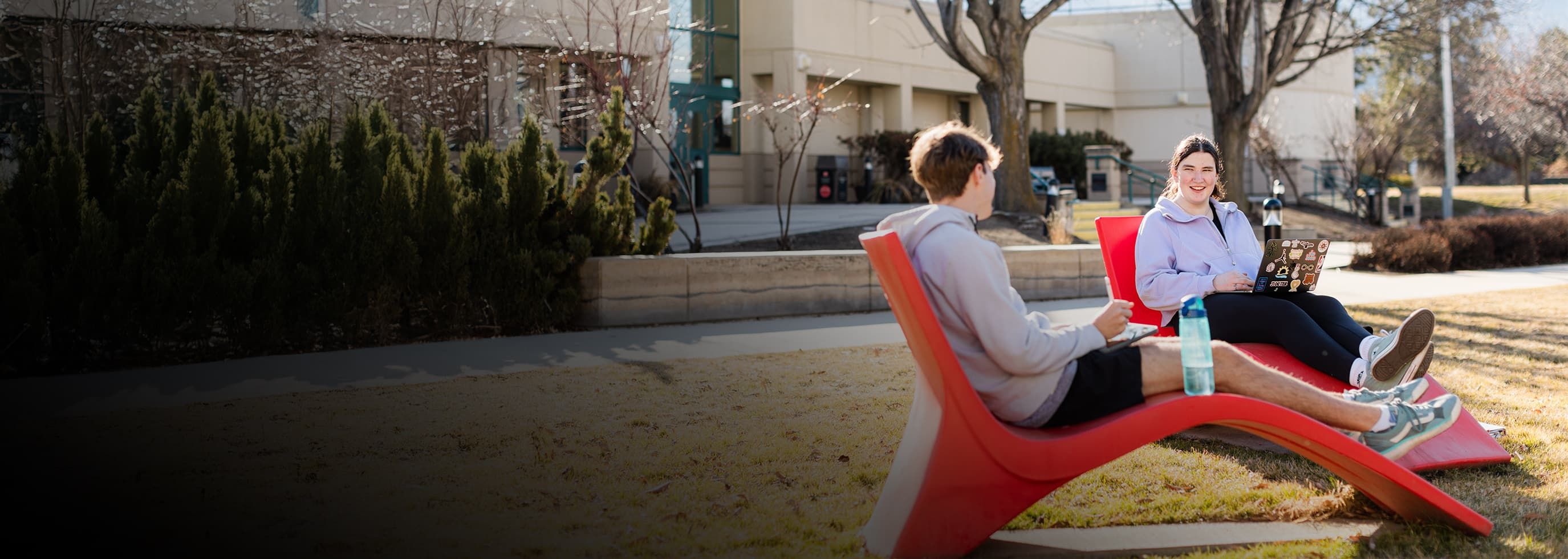 OC students relaxing on a red lawn chair.