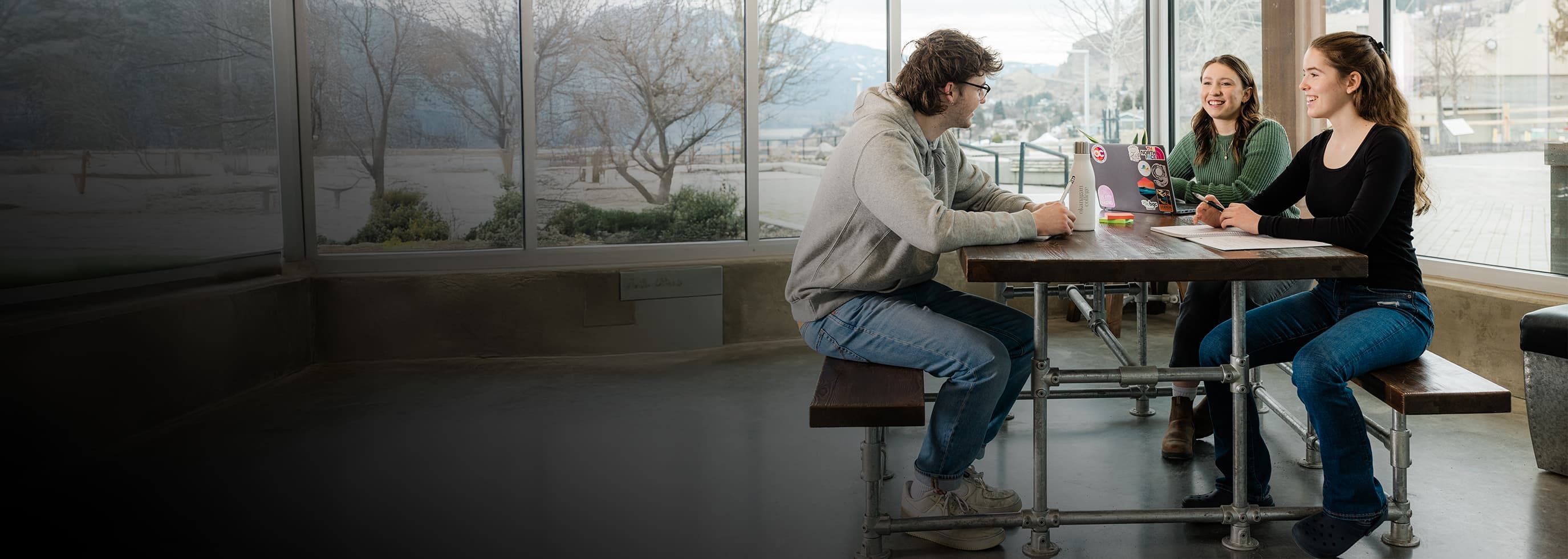 OC students sitting around a table, chatting and smiling.