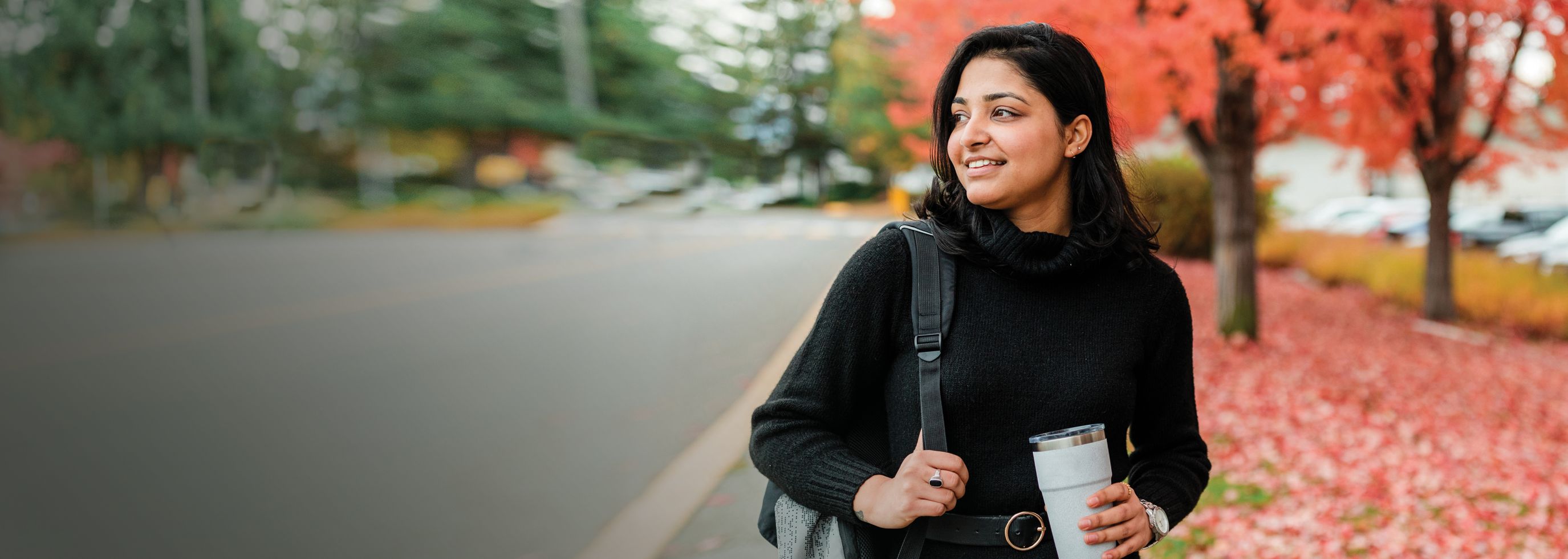 A woman looking ahead with fall foliage in the background