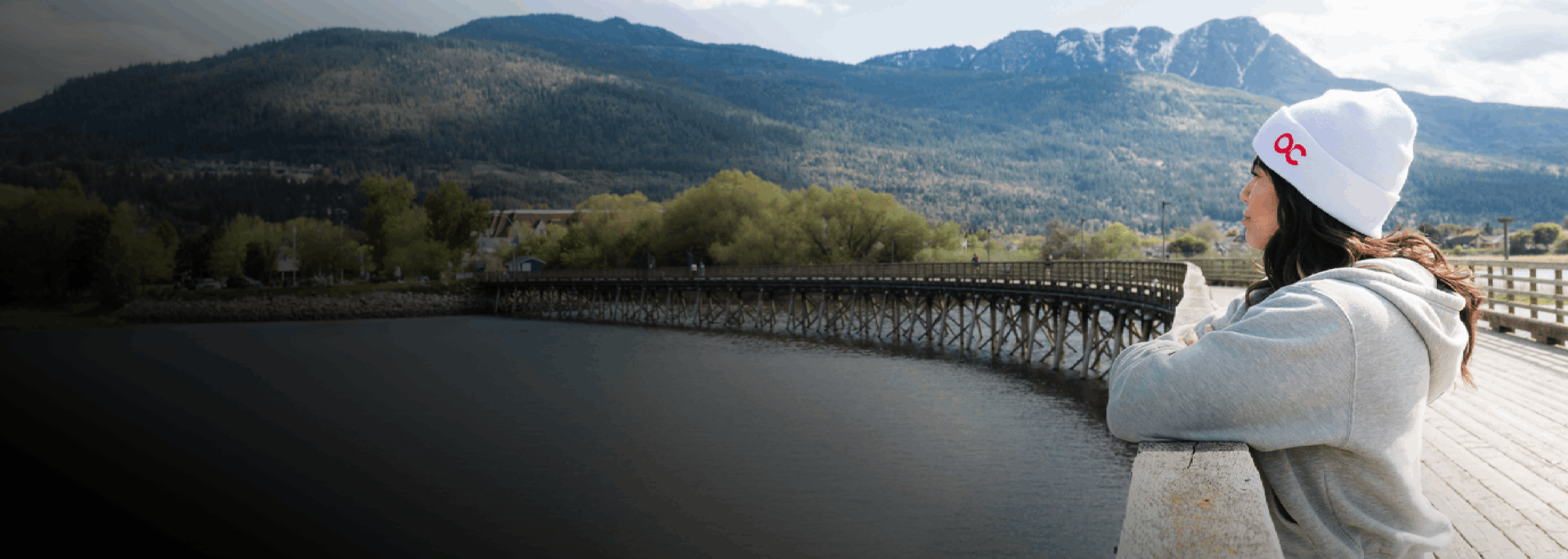 A woman looking over a wharf with an OC beanie
