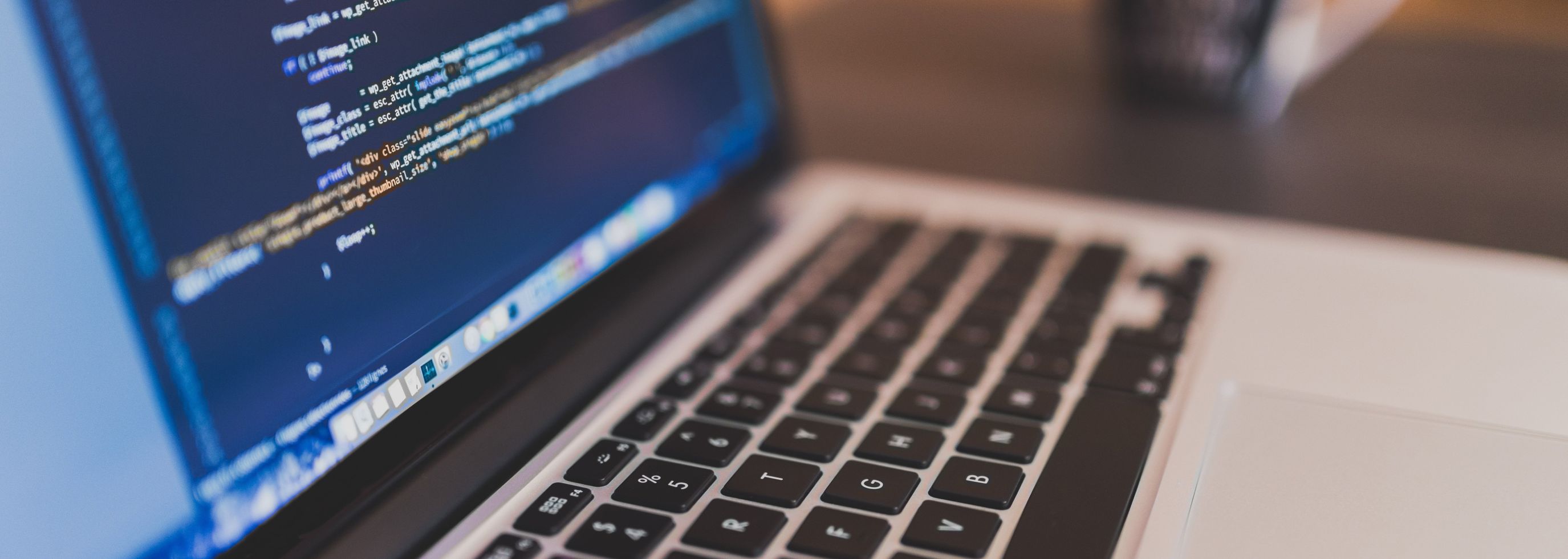 Laptop with some code on the screen and a blurred cup on the background.