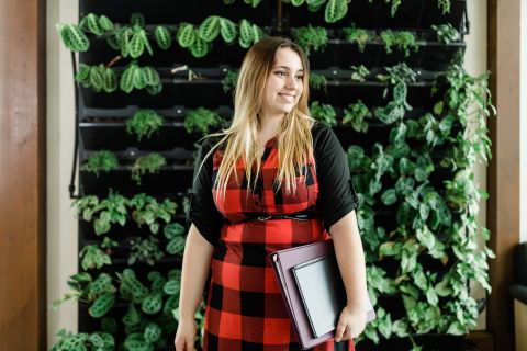 Student standing in front of a living wall growing plants