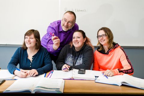 A group of female students are working in a classroom and an instructor is behind helping them.