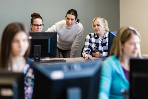 A group of students work in a computer lab on computers. 