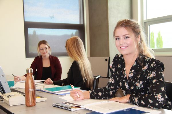 Female student wearing a blue winter coat standing outside.