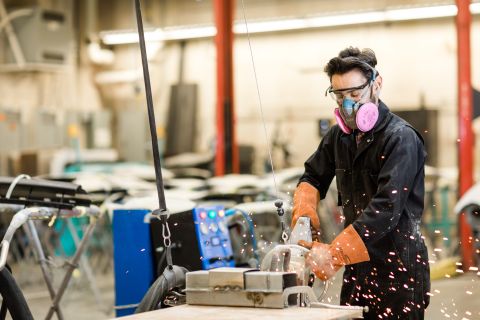 Collision Repair student grinds material to smooth the finish.