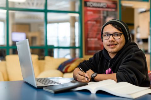 student sitting with laptop and papers