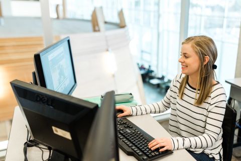Computer Information Systems student works behind two monitors