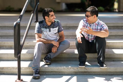 Two male students sitting on campus stairs