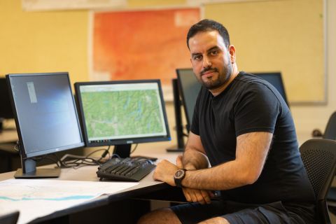 student sitting at a computer with papers