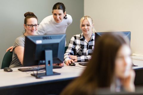two students with instructor in a computer lab