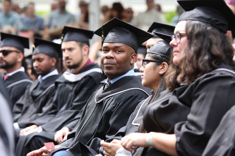 male graduating student in gown with other graduates