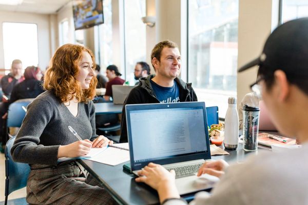 Three students studying as a group in the cafeteria on the Kelowna campus