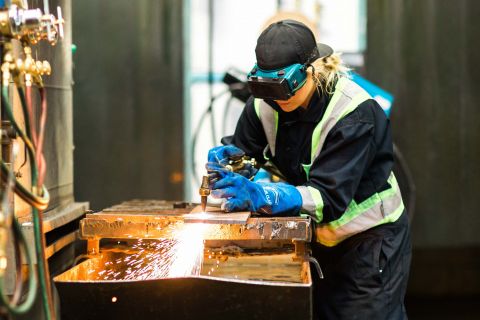 Welding student works on a project with sparks flying