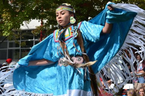 A young Indigenous dancer spreads her arms in the rhythm of the moment.
