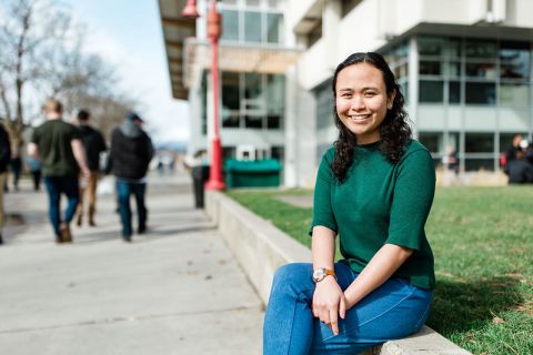 A female student sits outside of the Centre for Learning in Kelowna.