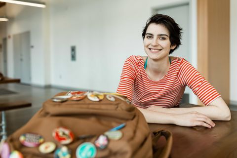 Arts student sitting at a table with a backpack in front of her.