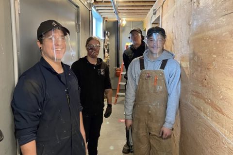 Piping and plumbing students at the Kelowna campus stand in a hallway where they've been working