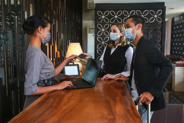 Two people checking into a hotel handing a credit card to hotel staff standing at a desk