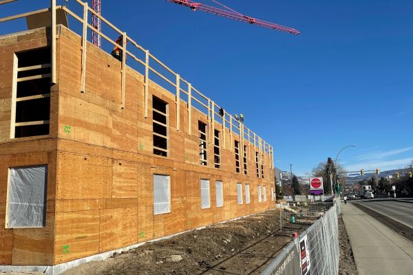Student housing building under construction - plywood walls are visible on the new building in front of a vibrant blue sky