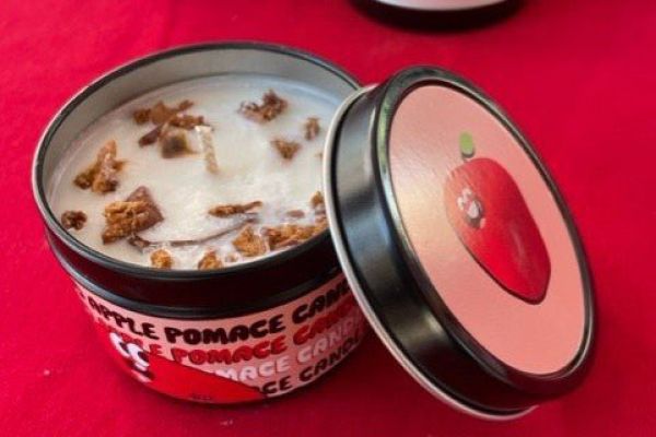 Candle in a jar open to show wick displayed on a red table