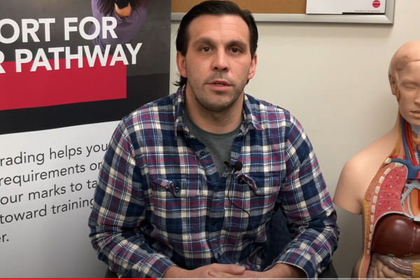 Adrian seated in front of an upgrading sign