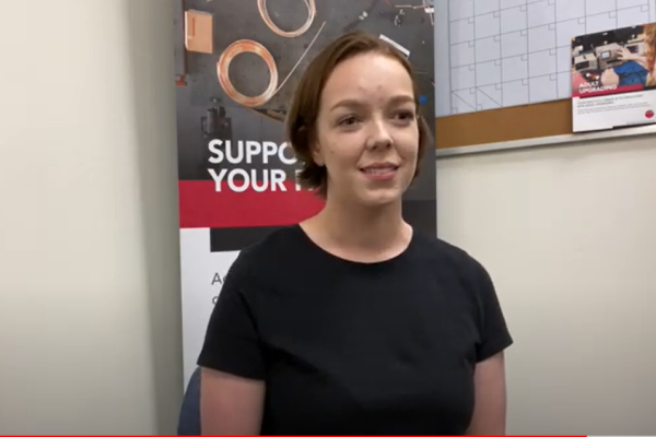 Anna May in front of an Adult Upgrading sign