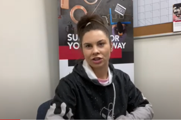 Courtney explains the value of upgrading while seated in front of an Pathways banner