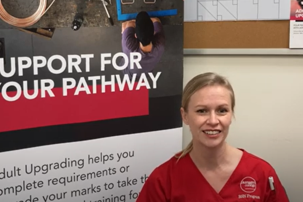 Emma in scrubs in front of an upgrading sign