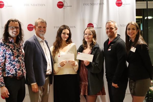 People standing with cheques that were given to students