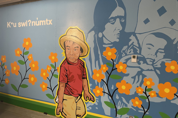 painted mural with blue background, orange flowers, a young boy, and a woman and baby