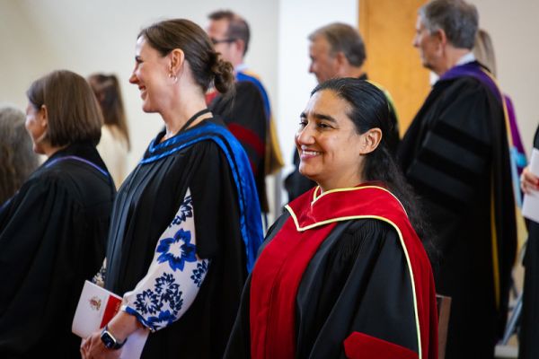 two College employees standing at convocation ceremony