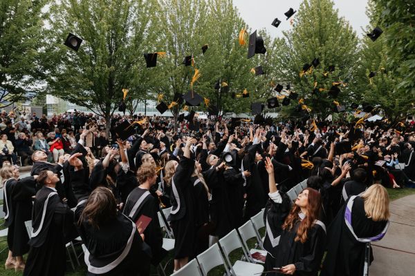 Okanagan College Graduates throw their graduation caps in the air to celebrate - Kelowna