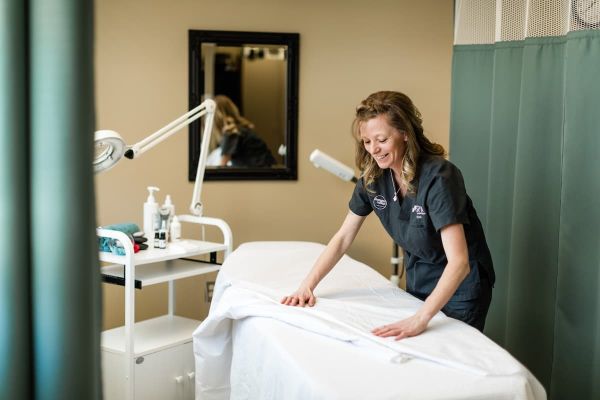 person flattening a sheet over a spa bed