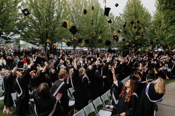 Graduates toss their caps during their June commencement ceremony.