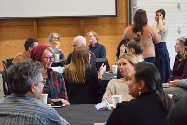 Group of community members sitting around tables in discussion 