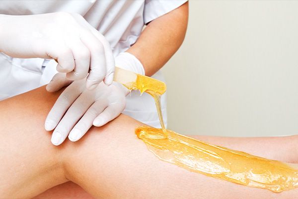 Side view of a leg with wax being applied to it by a spa practictioner